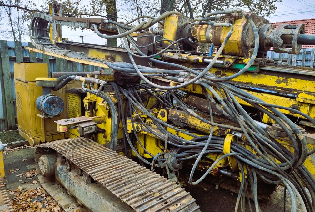 Pravý bok vrtné soupravy HVS 6132 před opravou, znečištěná hydraulika a neuspořádaná kabeláž.

